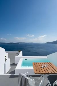 a villa with a swimming pool and a table and chairs at Katikies Villa Santorini - The Leading Hotels Of The World in Oia