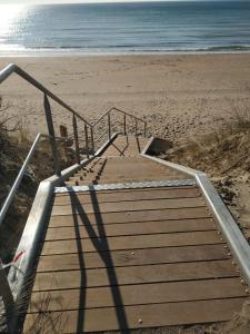 een houten trap naar het strand met de oceaan bij Le-Grand-Air 