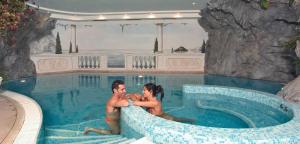 a man and a woman sitting in a swimming pool at Hotel Tonnerhof in Racines