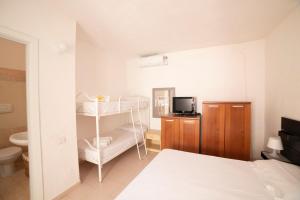 a white bedroom with a bed and a bathroom at Monolocale Free Beach Residence due passi dal mare in Costa Rei