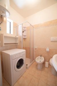a bathroom with a washing machine and a toilet at Monolocale Free Beach Residence due passi dal mare in Costa Rei