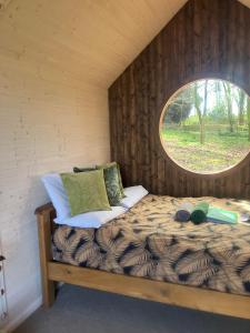 Bett in einem Zimmer mit rundem Fenster in der Unterkunft Sugi wooden pod in York