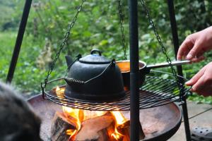 a person cooking a hat on a grill over a fire at Sugi wooden pod in York