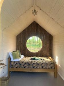 Cama en habitación pequeña con ventana en Sugi wooden pod, en York