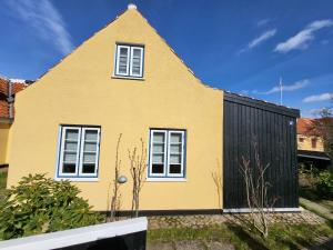 a yellow house with a black fence at Tinghus Flat in Skagen