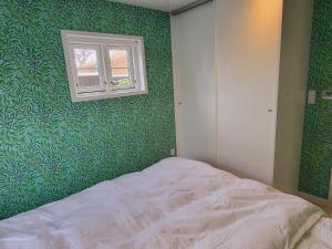 a bedroom with green walls and a bed with a window at Tinghus Flat in Skagen