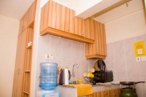 een keuken met houten kasten en een blauwe waterkan op het aanrecht bij Adeti Homestay in Ruiru