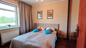 a bedroom with a bed with blue pillows and a window at Apartament Modern Life w centrum z parkingiem in Jelenia Góra