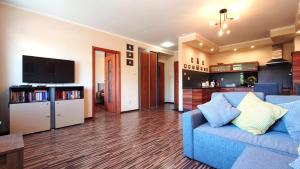uma sala de estar com um sofá azul e uma televisão em Apartament Modern Life w centrum z parkingiem em Jelenia Góra