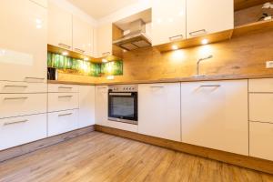 an empty kitchen with white cabinets and wooden floors at Appartment Klaus in Zellbergeben