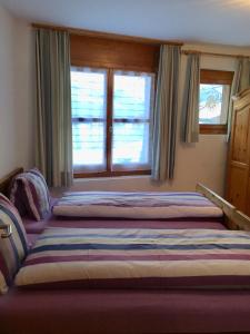 sypialnia z 2 łóżkami i 2 oknami w obiekcie Sut baselgia w mieście Andeer
