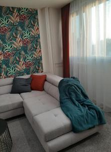 a living room with a couch with a blanket on it at Apartman Sunset in Osijek