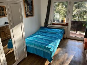 um quarto com uma cama azul num quarto com janelas em Ferienwohnung Fuchsblick em Altenau
