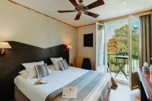 1 dormitorio con 1 cama, ventilador de techo y ventana en Hôtel L'Iroko The Originals City, en Aix-les-Bains