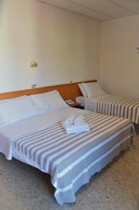 two beds in a hotel room with towels on them at Hotel Villa Paolina in Pietra Ligure