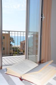 an open book sitting on a table in front of a window at Hotel Villa Paolina in Pietra Ligure