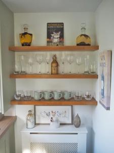 półka pełna okularów i innych przedmiotów szklanych w obiekcie Good stay at 91 w mieście Silsden