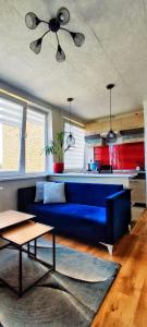 a living room with a blue couch and a kitchen at R&J Apartment II in Panevėžys
