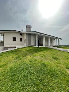 una casa bianca con un grande campo verde di fronte di Gomes Comfort House 2 a Valeggio sul Mincio