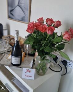 a vase of red roses on a counter with a bottle of wine at Il Paradiso del Relax Chambres d'hotes Affittacamere room with sea view in Sanremo