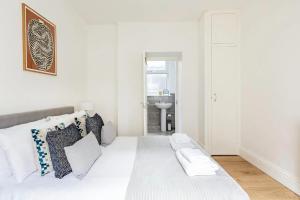 a white bedroom with a bed and a sink at Stylish one bedroom apartment in Greater London in London