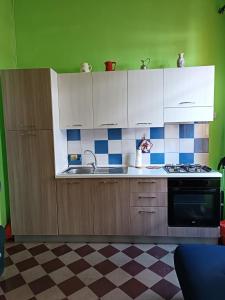 a kitchen with white cabinets and blue and white tiles at Casa Colombini in Iglesias