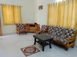 a living room with two chairs and a couch and a table at Vrundavan in Panchgani