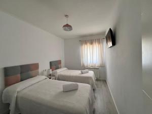 een hotelkamer met 2 bedden en een televisie bij El descanso de la Covatilla in Béjar