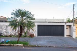 a garage with a palm tree in front of a house at Casa Espaçosa com Jacuzzi e Churrasqueira RAU409 in Goiânia
