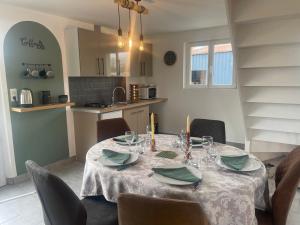 a dining room table with a white table cloth and chairs at Gîte de campagne in Yvetot Bocage