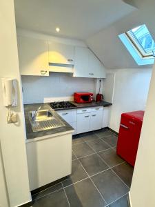 una pequeña cocina con nevera roja y armarios blancos. en Grand Place Apartement, en Bruselas