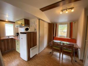 a small kitchen and dining room with a table and chairs at Camping Cascade Aveyron in Saint-Rome-de-Tarn