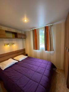 a bedroom with a purple bed and a window at Camping Cascade Aveyron in Saint-Rome-de-Tarn