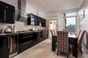 a kitchen with black cabinets and a table and chairs at 56 Hawkhill Avenue in Ayr