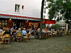a group of people sitting at tables outside a restaurant at cosy loft in town house in Paris