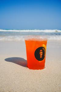 una taza naranja sentada en la arena de la playa en Tunich Jungle Cabañas en Tulum