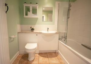 a bathroom with a toilet and a sink and a tub at Corner Cottage in Shaftesbury