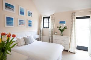 a white bedroom with a white bed and flowers at Corner Cottage in Shaftesbury