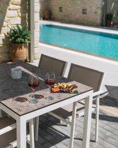 a table with two glasses of wine and a plate of food at Matala Prime Villas in Matala