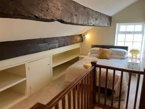 um quarto com uma cama e uma escada com uma estante em Steeple View - A two bedroom 18th century cottage. em Leeds