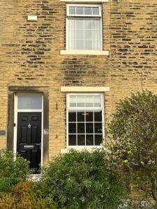 a brick building with a black door and two windows at Steeple View - A two bedroom 18th century cottage. in Leeds