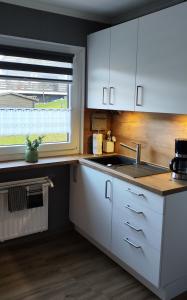 een keuken met witte kasten, een wastafel en een raam bij Top Ferienwohnung am Diemelsee Sauerland in Diemelsee