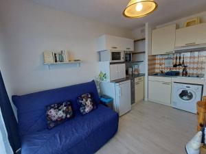 uma sala de estar com um sofá azul e uma cozinha em Appartement Balaruc-les-Bains, 1 pièce, 2 personnes - FR-1-571-24 em Balaruc-les-Bains