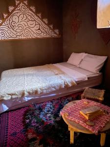 Un dormitorio con una cama y una mesa sobre una alfombra en Dar Laassri Tours, en Mhamid