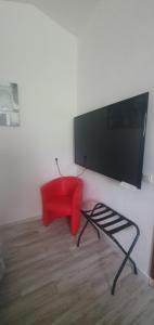 een woonkamer met een rode stoel en een flatscreen-tv bij Chez Dom & Albert in Saint-Cézaire-sur-Siagne