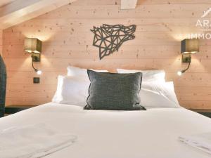 een slaapkamer met een wit bed en een houten muur bij Chalet Le Grand-Bornand, 3 pièces, 8 personnes - FR-1-391-168 in Le Grand-Bornand