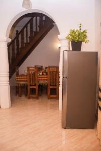 a kitchen with a refrigerator and a table with chairs at B&B Shenal Villa Kosgoda in Kosgoda