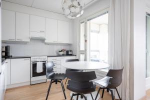 eine weiße Küche mit einem Tisch und Stühlen in der Unterkunft 2 BR apartment with Sauna, Free parking and center location in Tampere
