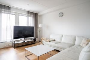 ein Wohnzimmer mit einem weißen Sofa und einem Flachbild-TV in der Unterkunft 2 BR apartment with Sauna, Free parking and center location in Tampere