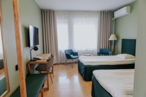 a hotel room with two beds and a tv at Hotel Fjalar in Salo